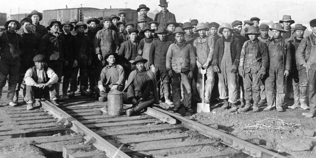 About fifty Chinese labourers posing by a segment of railroad track that they had built as part of the original Canadian National Railroad.